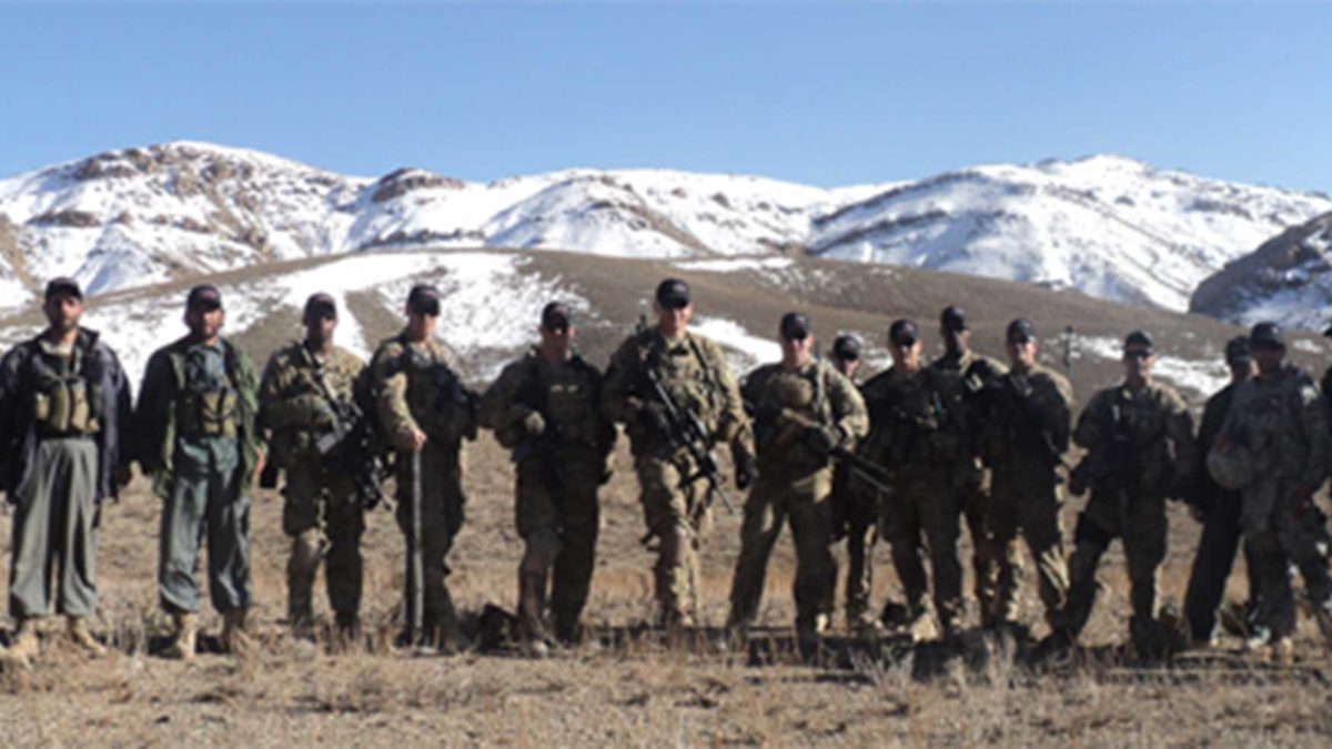 Members of the US Military posing in front of snow capped hills