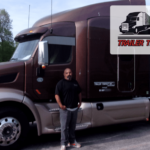 Trailer Transit Inc. | A man stands next to a large brown semi-truck with the text "Owner Operator of the Month" and "Trailer Transit Inc." proudly displayed in the upper right corner.