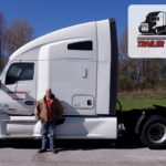 Trailer Transit Inc. | A person stands proudly in front of a white semi-truck emblazoned with the Trailer Transit Inc. logo and a sign that reads "Owner Operator of the Month."