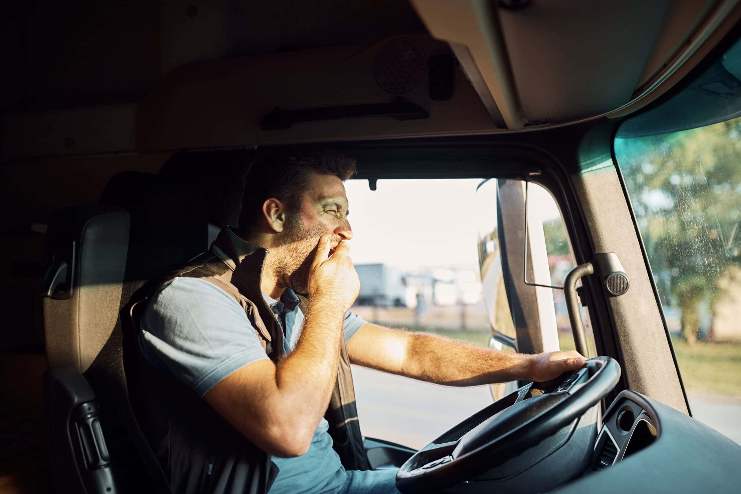 Trailer Transit Inc. | A truck driver yawning from fatigue while on the road.