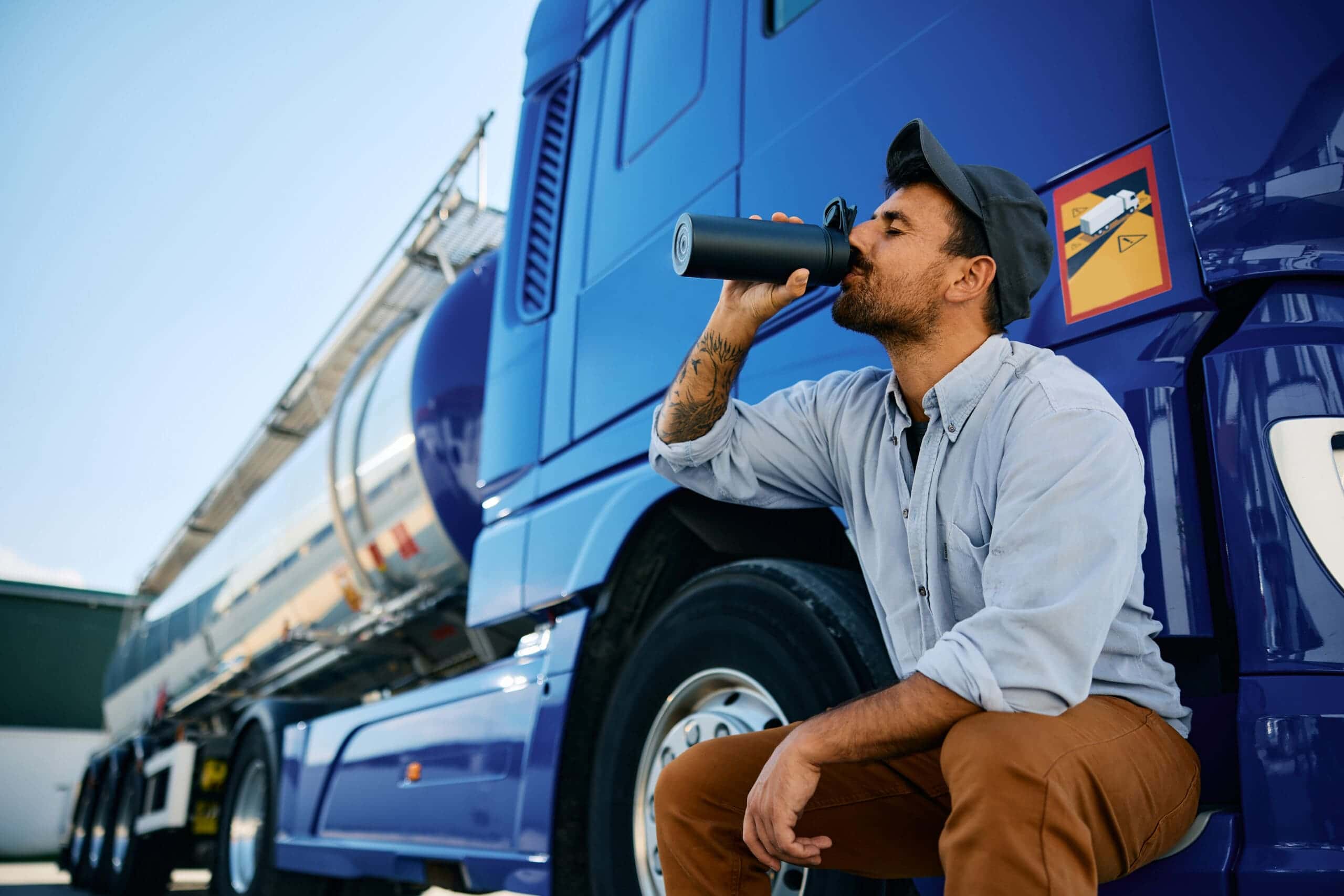 Trailer Transit Inc. | A truck driver drinking water outside his rig.