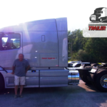 Trailer Transit Inc. | June's Owner Operator of the Month, Michael, stands in front of his truck; logo of Trailer Transit