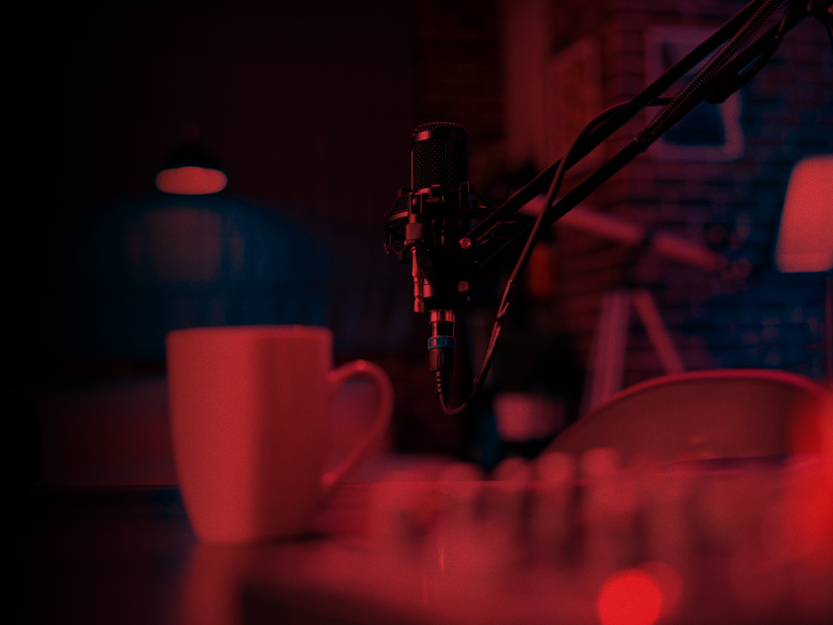 Trailer Transit Inc. | A microphone on a boom arm and a mug on a desk under dim red lighting.