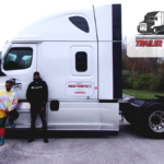 Trailer Transit Inc. | November Owner Operators of the Month stand proudly beside a white semi-truck adorned with the logo "Trailer Transit Inc." and a sign reading "Owner Operator of the Month," showcasing excellence in owner operator driving jobs.